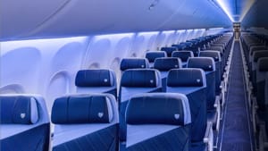 Aircraft cabin interior showing standard economy seats with armrests and aisle view