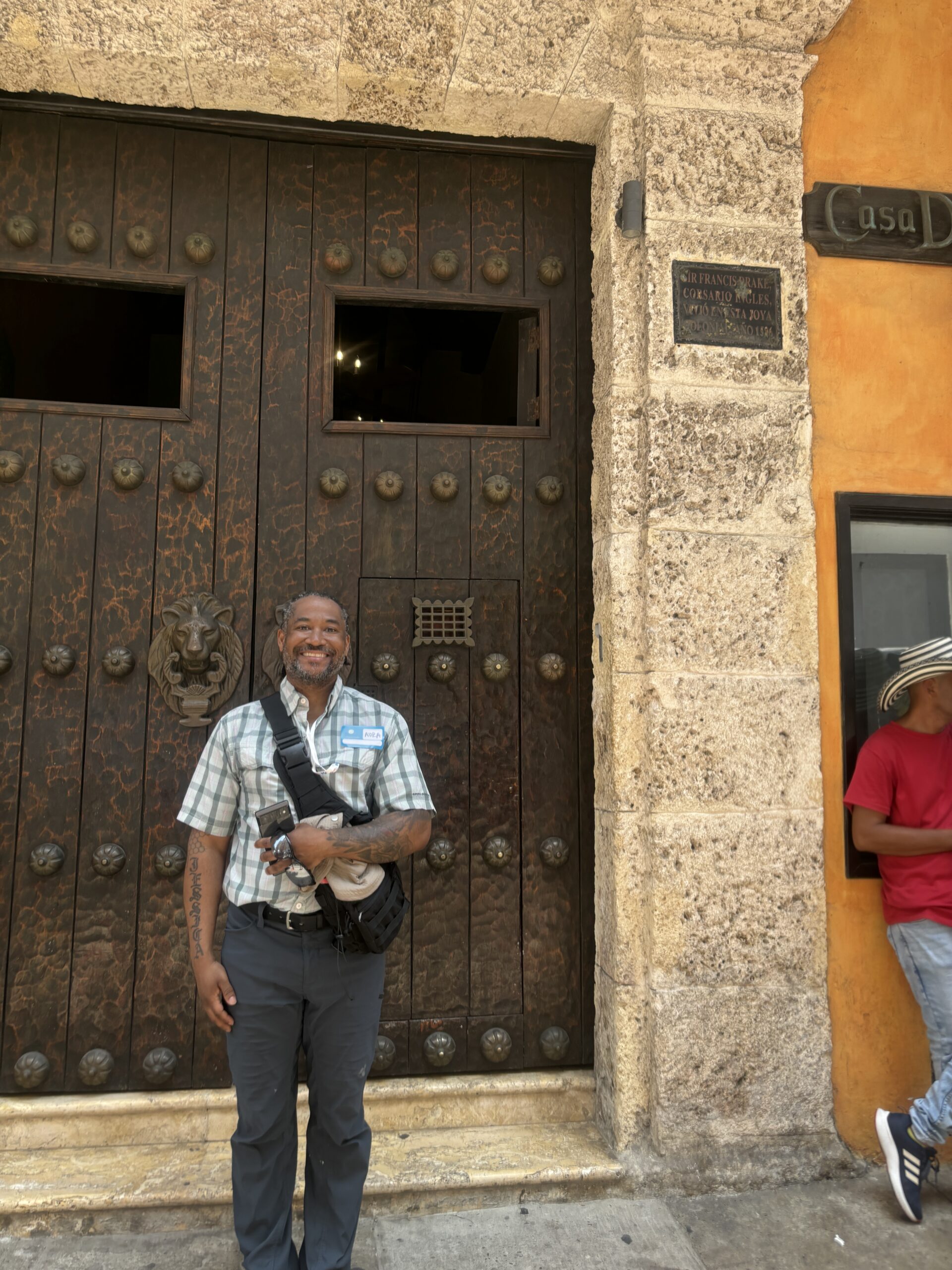 Traveler beside a stone plaque marking Sir Francis Drake's 1586 presence in Cartagena's walled Old City, Colombia