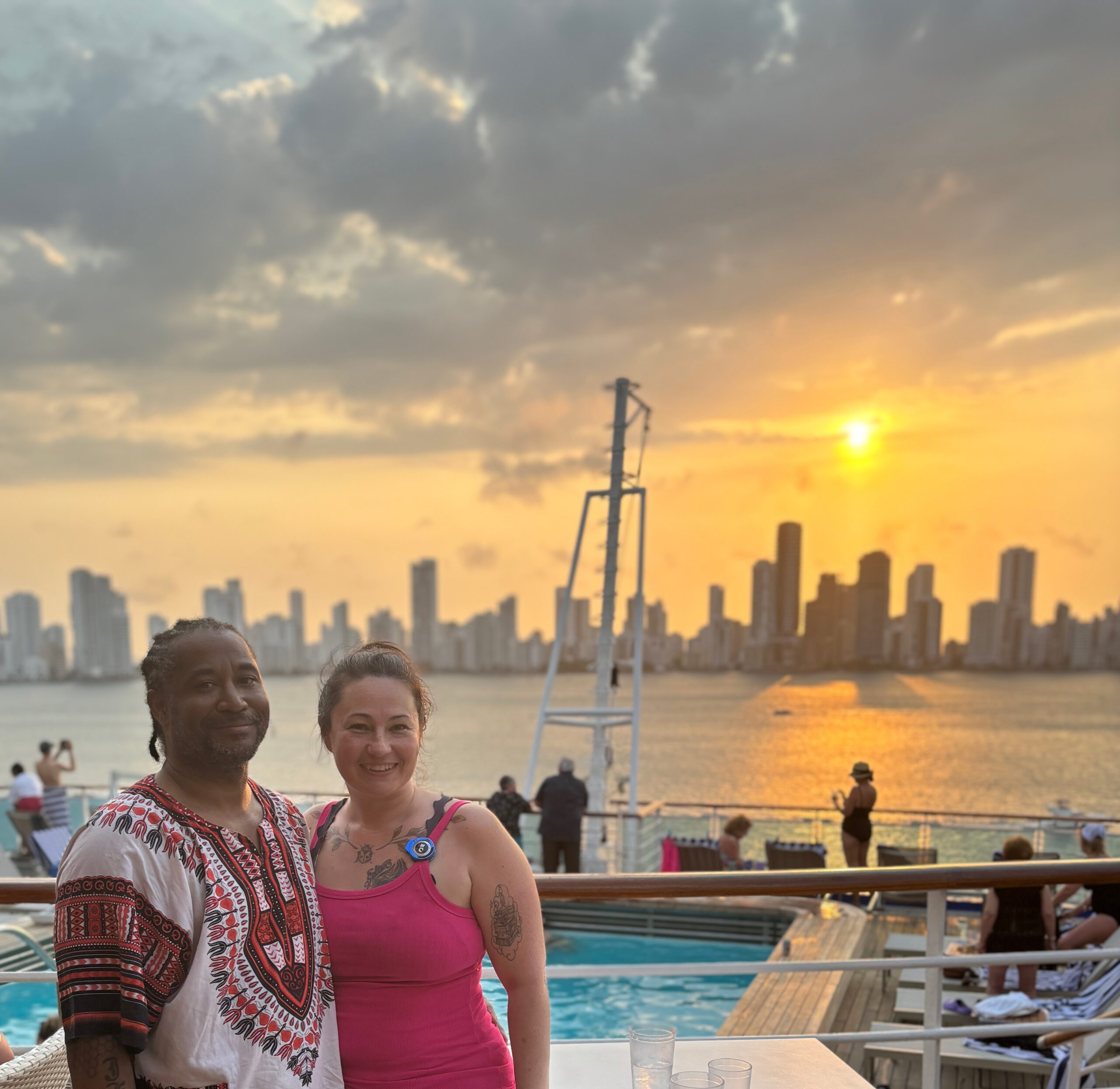 Jessica Gray and her husband on a cruise ship deck at sunset, with the Cartagena skyline across the water