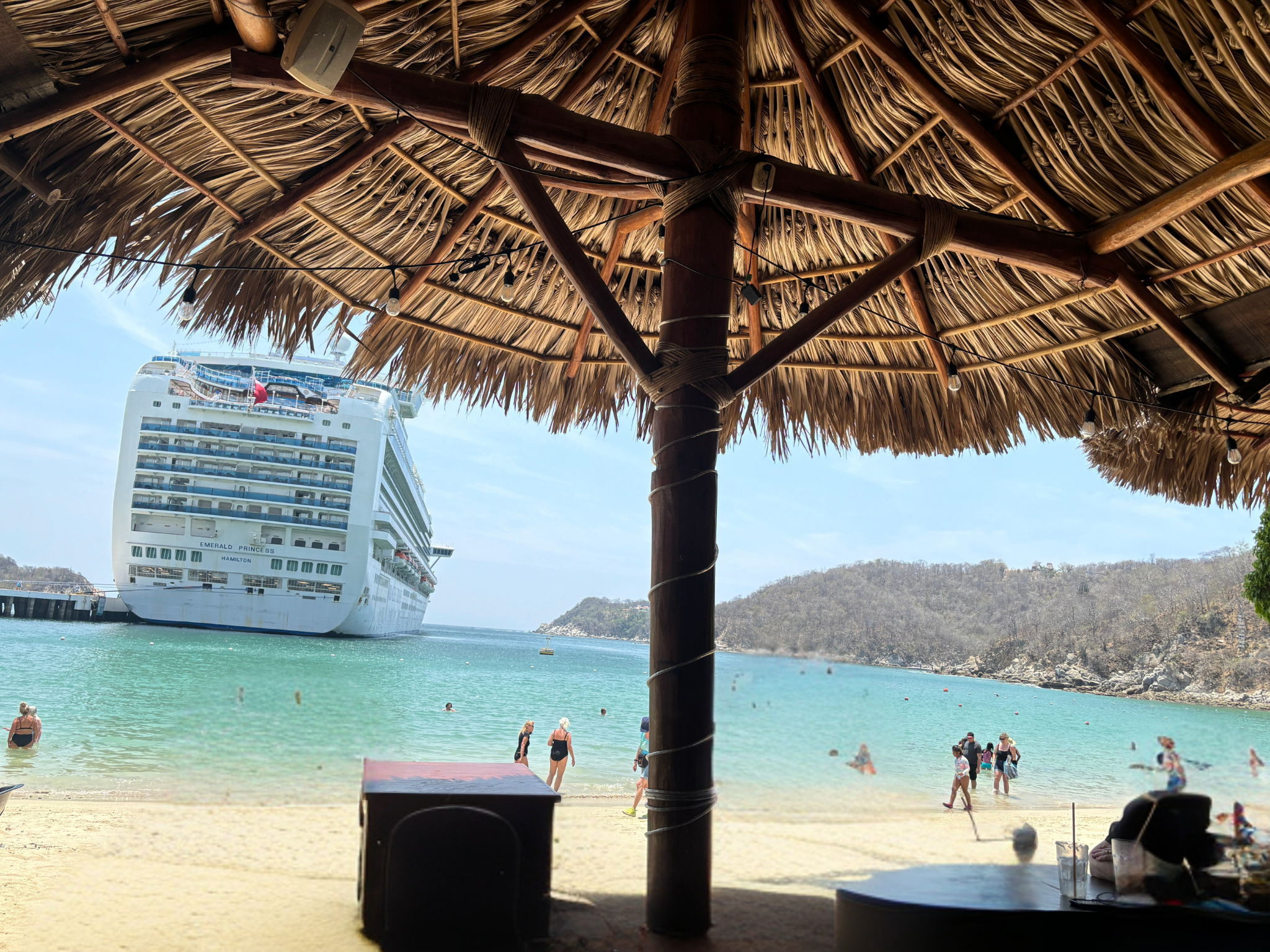 Cruise ship anchored at Huatulco seen from a beachfront palapa restaurant